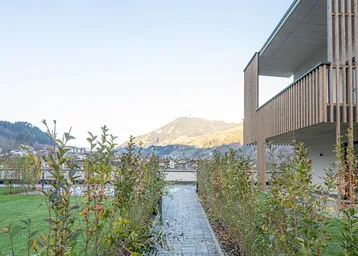 Neubau-Wohnanlage mit moderner Architektur und weitem Blick auf die umliegende Berglandschaft.