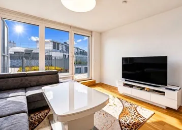 Helles Wohnzimmer mit großem Sofa, modernem Couchtisch und Zugang zu einer sonnigen Terrasse.