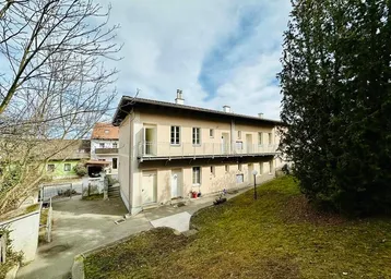 Mehrfamilienhaus mit mehreren Balkonen und einem gepflegten Vorgartenbereich.