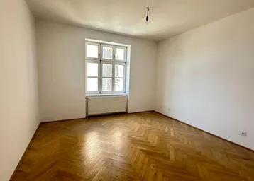 Helles Zimmer mit klassischem Fischgrätparkett und großem Fenster, bereit zur individuellen Gestaltung.