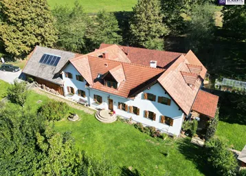 Luftaufnahme des weitläufigen Anwesens mit Haupthaus, Nebengebäuden und grüner Umgebung.