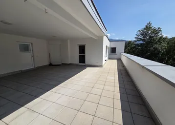 Geräumige, sonnige Terrasse mit Fliesenboden und Blick auf die umliegende Natur.