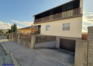 Hausfassade mit integrierter Garage und Zufahrt unter blauem Himmel.