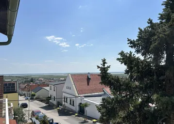 Panoramablick über die Dächer der Häuser auf eine weite Wasserlandschaft in der Ferne.
