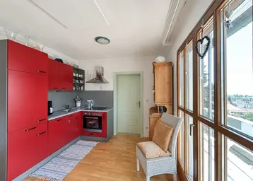 Funktionale Küche mit roten Schränken, integriertem Backofen und hellem Holzboden.