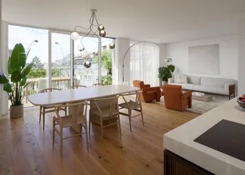 Helles, offenes Wohn-Esszimmer mit Holzboden, modernen Möbeln und Zugang zu einem großen Balkon.