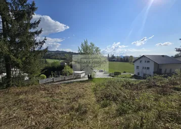 Weitläufige Landschaft mit grünen Feldern, Bäumen und einem Haus in der Ferne unter blauem Himmel.