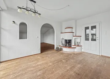 Geräumiges Wohnzimmer mit Holzboden, Kamin und traditionellen Details.