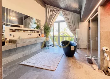 Luxuriöses Badezimmer mit freistehender Badewanne, großer Dusche und Balkonzugang.