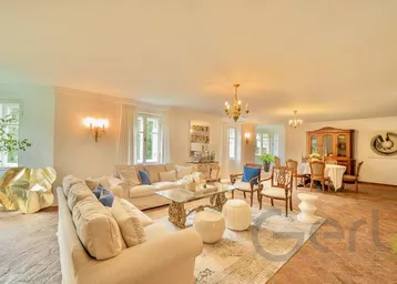 Großzügiger Wohnbereich mit eleganten Sofas, Kunstwerken und Blick in den Essbereich.