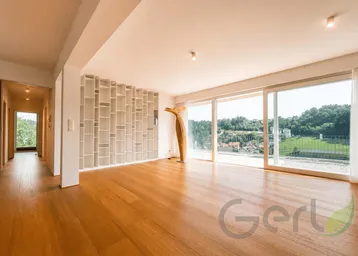 Helles Wohnzimmer mit Holzboden, großen Schiebetüren und weitem Blick ins Grüne.