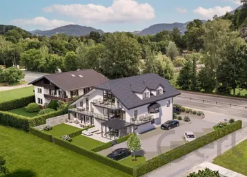 Luftaufnahme eines modernen Wohnhauses mit angrenzendem traditionellen Gebäude und gepflegter Gartenanlage.