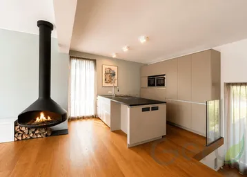 Moderne offene Küche mit Kochinsel und freistehendem Kamin in einem hellen Wohnbereich.