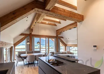 Geräumiger offener Wohnbereich mit Holzbalken, Seeblick und moderner Küche.