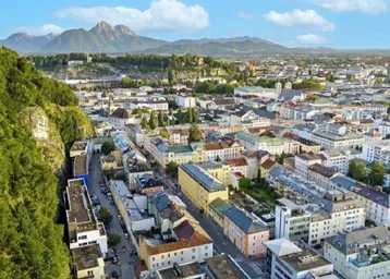 Panoramablick über eine Stadt mit historischen Gebäuden und majestätischen Bergen im Hintergrund.