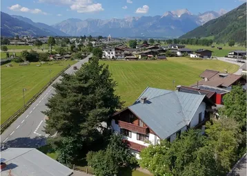 Luftaufnahme eines Hauses in ländlicher Umgebung mit beeindruckendem Bergblick und grünen Feldern.