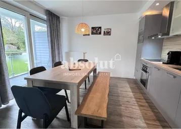 Moderner offener Wohn- und Essbereich mit integrierter Küche und Zugang zum Balkon.