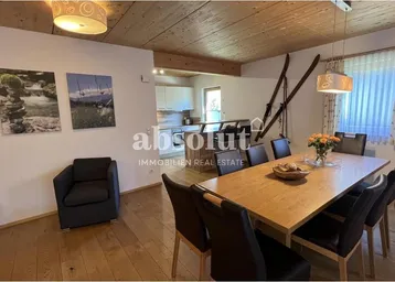 Geräumiger Wohn-Essbereich mit Holzboden, Holzbalkendecke und rustikalen Dekorationen.