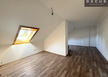 Helles Dachgeschosszimmer mit Laminatboden und Dachfenster, bereit für die individuelle Gestaltung.