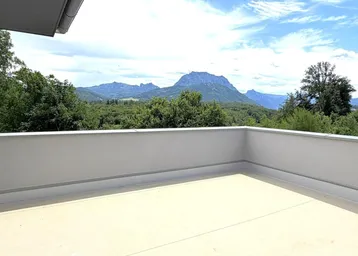 Geräumige Terrasse mit weitem Blick auf die umliegende Berglandschaft und den blauen Himmel.