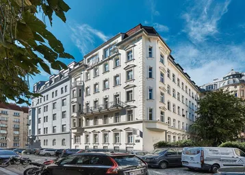 Mehrstöckiges Wohngebäude mit klassischer Architektur und Balkonen an einer städtischen Straße.