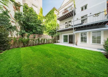 Grüner Rasen im Gartenbereich mit angrenzender Terrasse und Blick auf die Gebäudefassade.