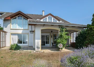 Hausfassade mit überdachter Terrasse, Sitzbereich und blühendem Lavendel im Vorgarten.