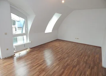 Helles Zimmer mit Dachschrägen, Laminatboden und großem Fenster, bereit zur individuellen Gestaltung.