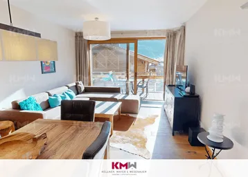 Helles Wohn- und Esszimmer mit gemütlichem Sofa, Holztisch und Zugang zum Balkon mit Bergblick.
