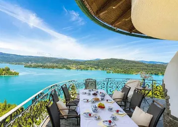 Geräumiger Balkon mit Esstisch und atemberaubendem Blick auf den See und die umliegende Landschaft.