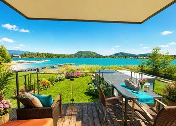 Geräumige Terrasse mit Holzboden, bequemen Möbeln und einem atemberaubenden Blick auf den See und die Berge.