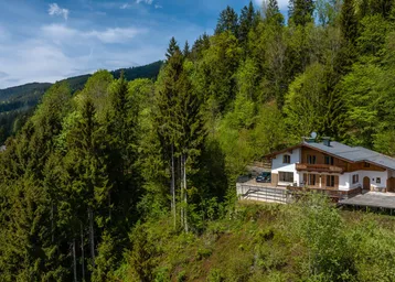Ein charmantes Chalet in den Bergen, umgeben von üppigen Wäldern und grüner Natur.