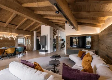 Geräumiger Wohn- und Essbereich mit Holzbalkendecke, modernem Kamin und stilvollen Möbeln.