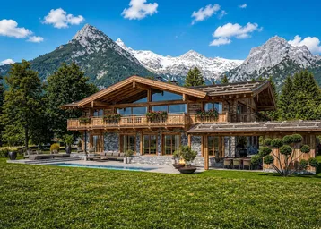 Luxuriöses Holzchalet mit Steinfassade, großem Pool und atemberaubendem Bergblick in alpiner Landschaft.