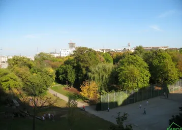 Weitläufiger Blick auf einen grünen Park mit Spielplatz und Sportplatz in der Stadt.