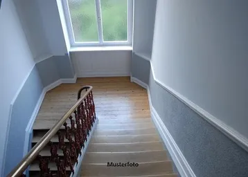 Helles Treppenhaus mit Holzgeländer, Holzfußboden auf dem Podest und einem Fenster für natürliches Licht.