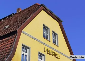 Gelbe Fassade eines älteren Gebäudes mit traditionellem Ziegeldach unter blauem Himmel.