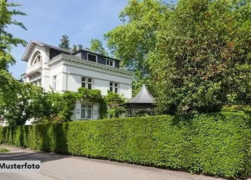 Klassische weiße Villa mit gepflegter Hecke und üppiger Begrünung in sonniger Umgebung.