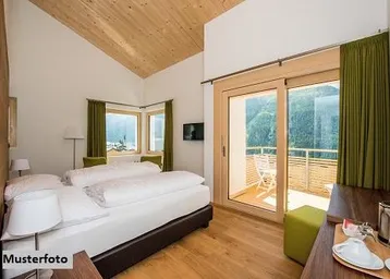 Helles Schlafzimmer mit Holzboden, Dachschräge und Zugang zu einem Balkon mit Bergblick.