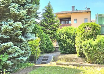 Gepflegter Gartenbereich mit üppiger Bepflanzung und Blick auf das Wohnhaus.