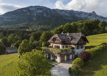 Idyllisches Landhaus in den Bergen mit traditionellem Holzdach und gepflegter Auffahrt.