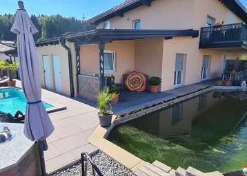 Großzügige Terrasse mit Swimmingpool, Naturteich und Blick auf die umliegende Landschaft.