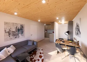 Offener Wohn-Essbereich mit Holzbalkendecke, modernem Sofa und integrierter Küche im Hintergrund.