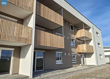 Modernes Mehrfamilienhaus mit Holzlamellenbalkonen und hellgrauer Fassade unter blauem Himmel.