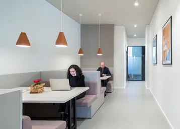 Modernes Büro mit Arbeitsnischen, Pendelleuchten und minimalistischer Einrichtung für konzentriertes Arbeiten.