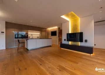 Moderne offene Küche und Wohnbereich mit Holzboden, integriertem Fernseher und indirekter Beleuchtung.