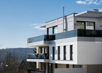 Ansicht der modernen Wohnanlage mit gestuften Balkonen, Glasgeländern und weitem Blick in die Landschaft.