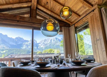 Eleganter Essbereich mit Bergblick durch große Fenster und stilvoller Beleuchtung.