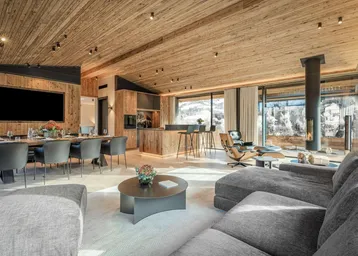 Geräumiger offener Wohn-Essbereich mit Holzakzenten, modernem Kamin und Panoramablick auf die Berge.