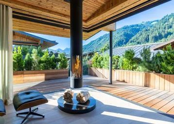 Überdachte Terrasse mit modernem Kamin, Holzdeck und atemberaubendem Bergblick.
